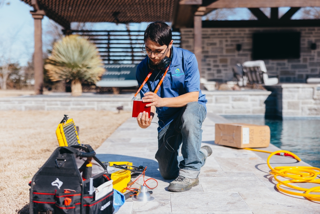 man kneeling by poolside for leak detection